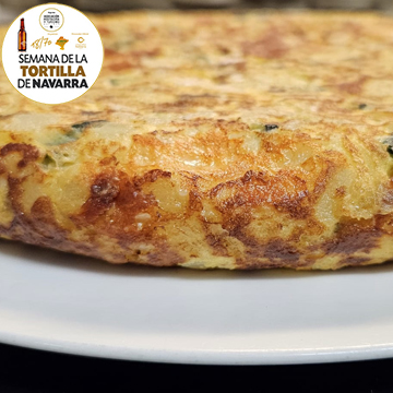 Tortilla de Patata con, llamada la Tortirella del Bar Caravinagre de Pamplona lleva los siguientes ingredientes: Calabacin, cebolla, tomate seco, provolone, parmesano, aceite de trufa y pistachos.